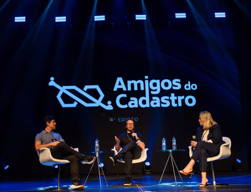 Mesa redonda con tres invitados sentados en el escenario, bajo el logotipo del evento