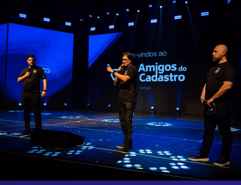 Tres panelistas de pie en el escenario de Amigos do Cadastro