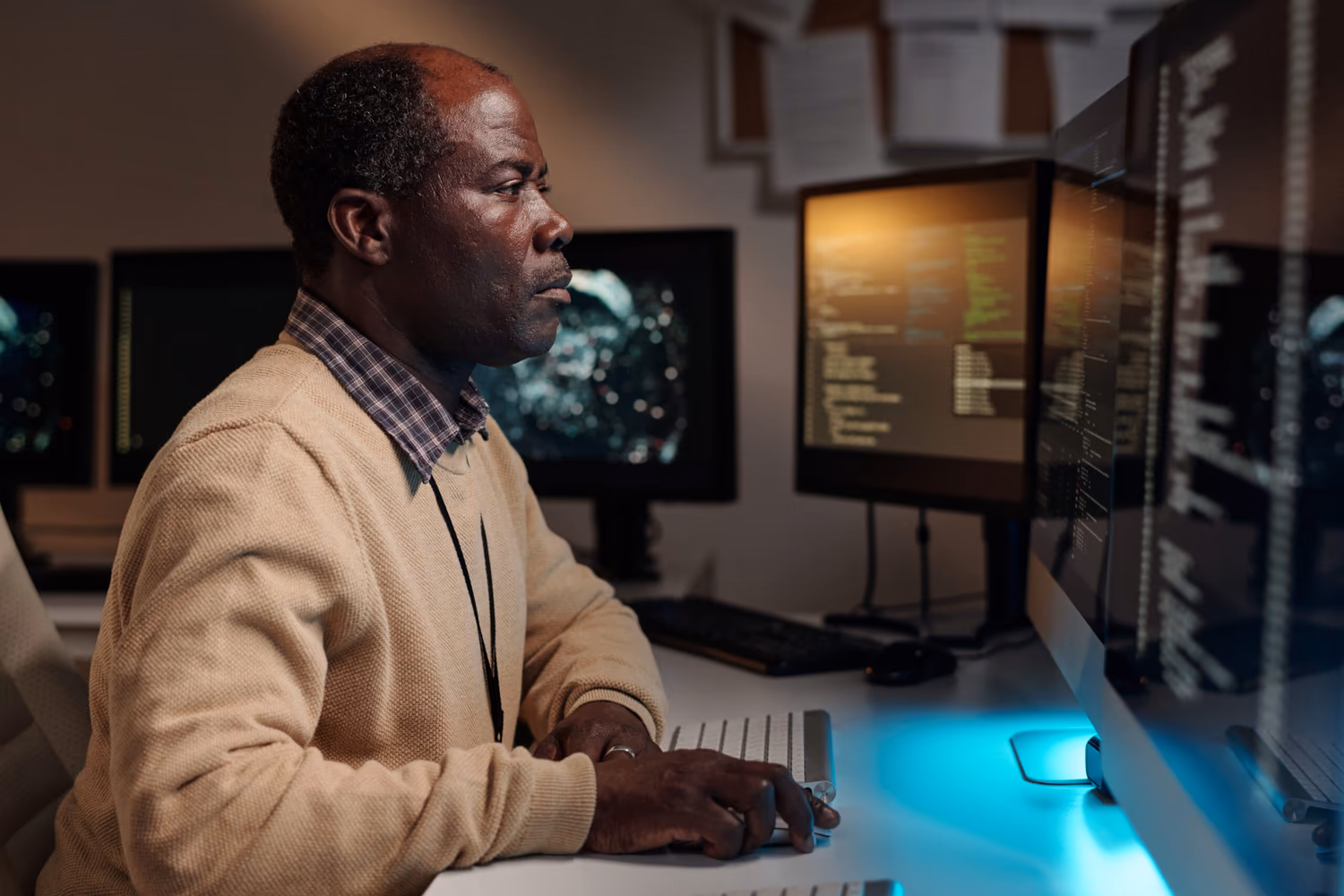 Hombre sentado frente a múltiples monitores con gráficos en la pantalla. Parece concentrado, demostrando un trabajo analítico y estratégico en un escenario "data-driven", donde las decisiones se guían por datos e información precisa.